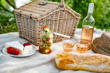 Summer picnic on blanket with delicious food and a bottle of rosé wine. Close-up.