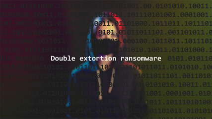 Cyber attack double extortion ransomware text in foreground screen, anonymous hacker hidden with hoodie in the blurred background. Vulnerability text in binary system code on editor program.