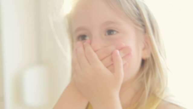 sweet child 5 years old, shy blonde girl covered mouth with hands, struggle to keep secret and maintain self-discipline, control difficulties, Mind your words
