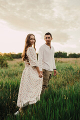 Fototapeta premium A married couple in a field of wheat at sunset in the afternoon.