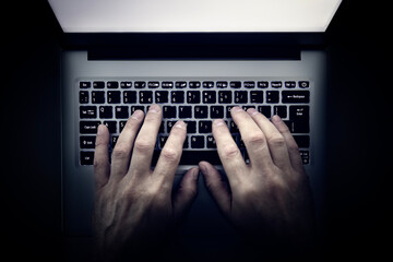 Using laptop from above searching internet, browsing information or hacker late at night in the dark