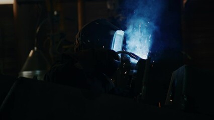 Welder in protective mask working with blow torch producing sparks and fume while welding metal at industrial factory - Powered by Adobe