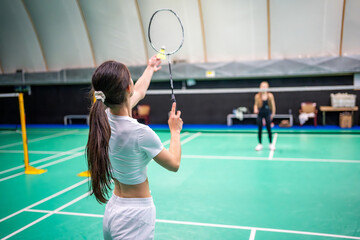 Sports young women with racket and shuttlecock is exercising, playing in badminton on inside court