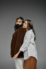 A loving couple dressed in stylish attire, posing with their arms around each other.