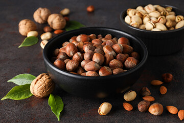 Different types of nuts in black bowls on a dark background