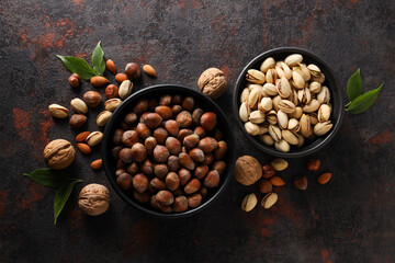 Different types of nuts in black bowls on a dark background