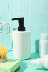 Dispenser for soap, brushes and bottles on blue background, close up