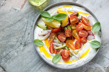 Tirokafteri or greek feta dip sauce with veggies, horizontal shot on a grey granite background, high angle view