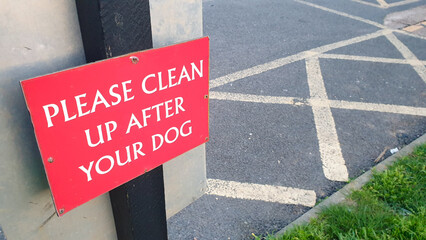 Red sign notice Please Clean Up After Your Dog in urban car park space