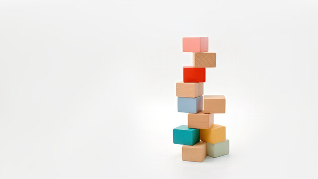 Stacked colorful wooden blocks arranged in a precarious tower on a white background.