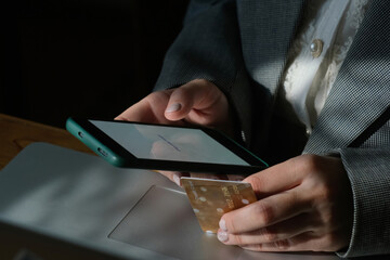 Person paying online using bank card and smartphone indoors