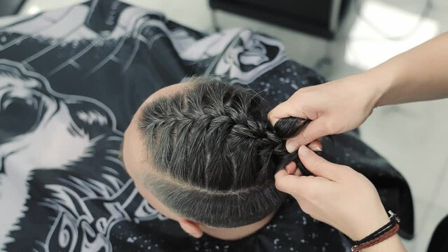 Braiding Hair Close-Up. Close-up view of hands braiding dark hair on a person's head with intricate patterns.