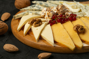 Cheese platter with various types of cheese and nuts on black background