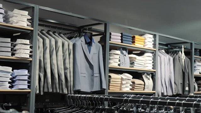 Men's clothing store display. A neatly organized display of men's clothing in a store, showcasing a variety of shirts, blazers, and folded garments on shelves and racks.
