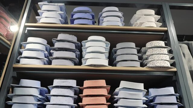 Stacked folded shirts in a store. Neatly stacked folded shirts in various colors and patterns on display shelves in a men's clothing store.