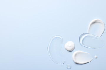 Samples of face cream on light blue background, top view. Space for text