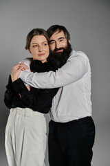 A loving couple dressed in elegant attire pose together for a portrait.