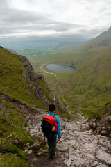Man is looking towards Devils Ladder, one of most difficult trails, that is leading to highest Irish mountain Carrauntoohill or Carrantuohill is the highest mountain in Ireland at 1038m