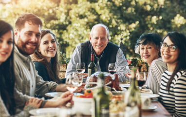 Family, portrait and happy for thanksgiving, dinner and celebration outdoor with food, wine and love. Group of people, smile and together at table for holiday, event and turkey with drink or eating