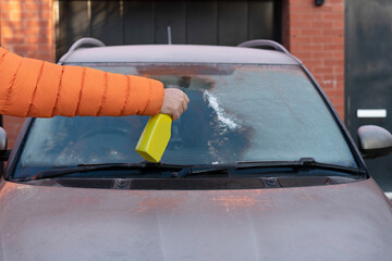 Person De-Icing Car Windshield With Spray Bottle on Cold Winter Day