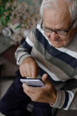 Grandpa is calling. An old man with gray hair speaks on the phone.	
