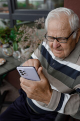 Grandpa is calling. An old man with gray hair speaks on the phone.	