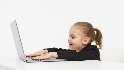 Little business girl child working or studying on a light background with a laptop. Modern online education, business and technology.