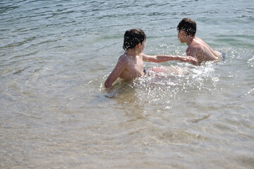 Happy children, aged 10-12, swimming and splashing in lake, river or sea, beach activity