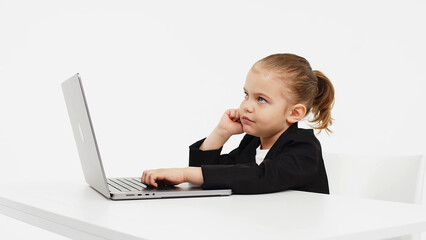 Business, little child working at a laptop on a light isolated studio background. Concept of deal, business and modern technology.