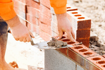 Construction Worker Laying Bricks With Mortar and Trowel on Building Site