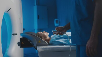 Slowmo midsection of unrecognizable male imaging specialist in uniform operating MRI machine by remote control using patient monitoring system. Caucasian woman undergoing diagnostic imaging procedure - Powered by Adobe