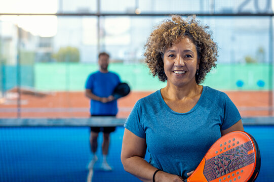 Portrait of woman playing padel with her friend on indoor court.