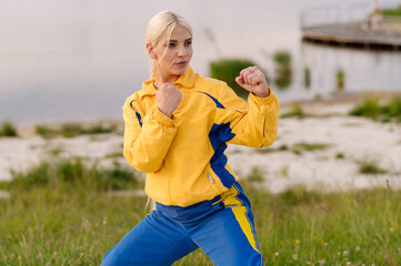 Strong woman karate fighter standing in fighting stance outdoors in park © rostyslav84