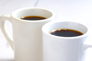 淹れたてのコーヒーが入ったふたつのマグカップで、二人が打ち合わせをしているイメージ