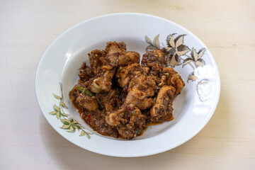 Delicious Irani chicken kadai bhuna curry on a white plate on wooden background. Tasty Iranian chicken kadhai recipe.