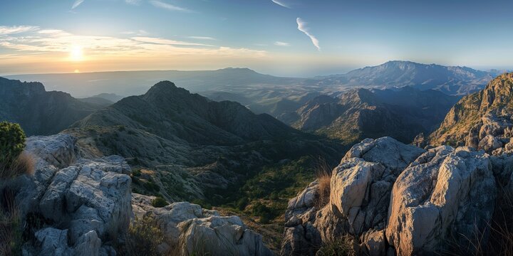 Capturing the serene moment of sunset over a panoramic landscape filled with rugged mountains and lush valleys