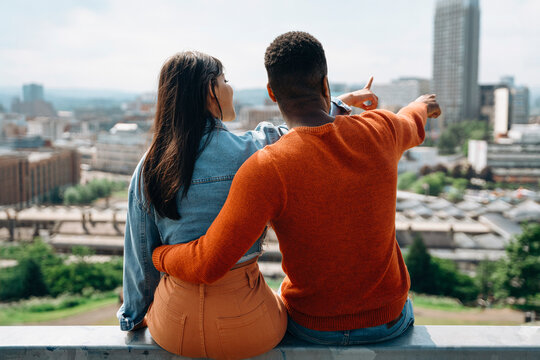Couple Sitting on Rooftop Overlooking City Skyline