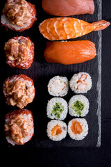 Sushi roll in tobiko caviar with salmon on a black board