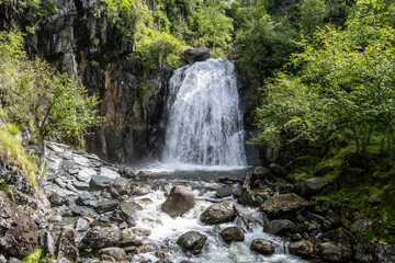 summer panoramic landscape of mountains and forest and waterfall against the sky in the area of ​​Lake Teletskoye in Altai