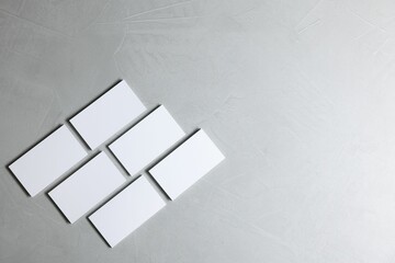 Blank business cards on light grey textured background, top view. Mockup for design