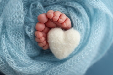  Closeup of toes, heels and feet of a newborn. Knitted white heart in the legs of baby. 