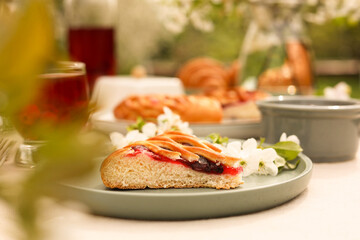 Stylish table setting with beautiful spring flowers, fruit drink and pie in garden