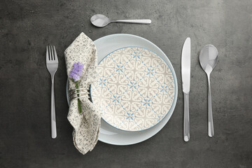 Stylish setting with cutlery and plates on black table, flat lay
