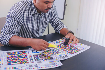 Worker checking print quality of media graphics proof print and color tone in printing industry....