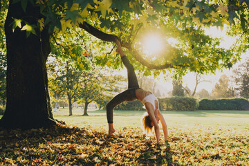 Young woman in casual wear doing yoga pose in park.