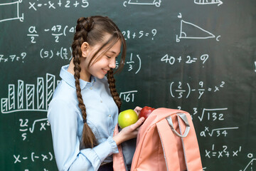 Schoolgirl teenager takes her school lunch out of her bag during break.