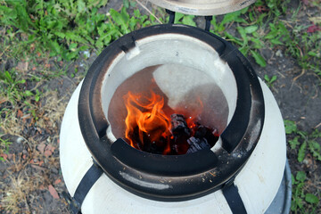 Tandoor, an ancient Asian clay oven for cooking, roasting meat and baking flatbreads. Close-up against green grass