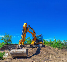 Crawler excavator on slope against blue sky. Land clearing, foundation digging, construction works. © Todayphoto