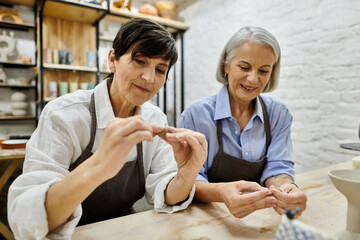 Two women work on pottery in a studio, focused on their craft.