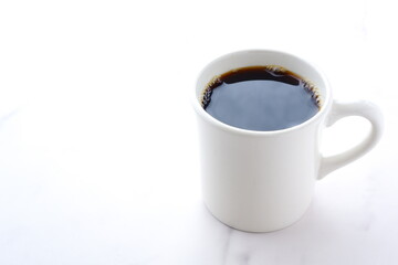 お気に入りのマグカップに淹れたてのコーヒーを入れ、一服を楽しむ朝の風景のイメージ
